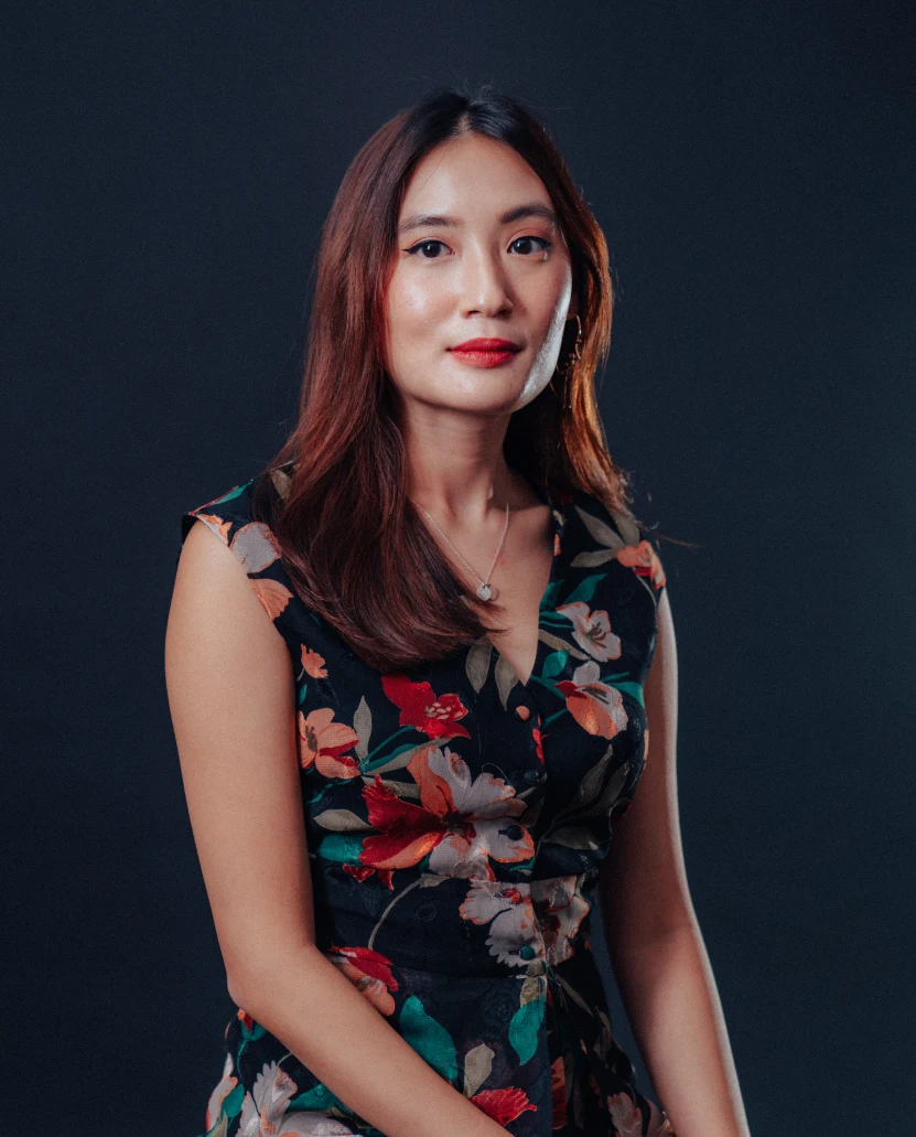 Portrait of Jolin Toh in a black floral dress against a dark backdrop