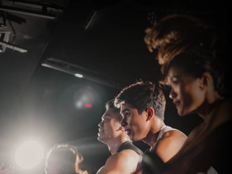 Riders mid-sprint in a dark cycling studio